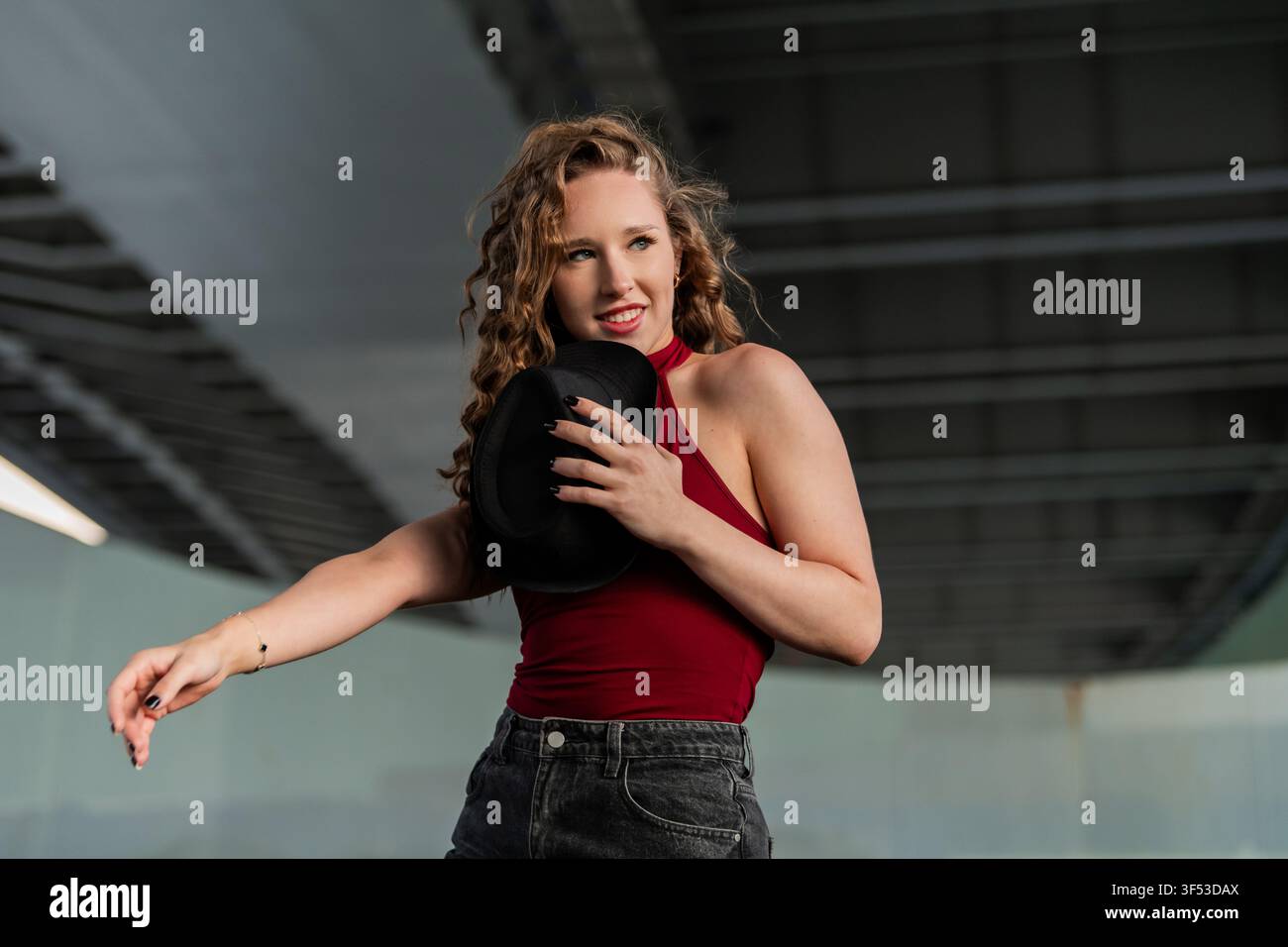 Stylish young woman with curly hair dances with a hat Stock Photo