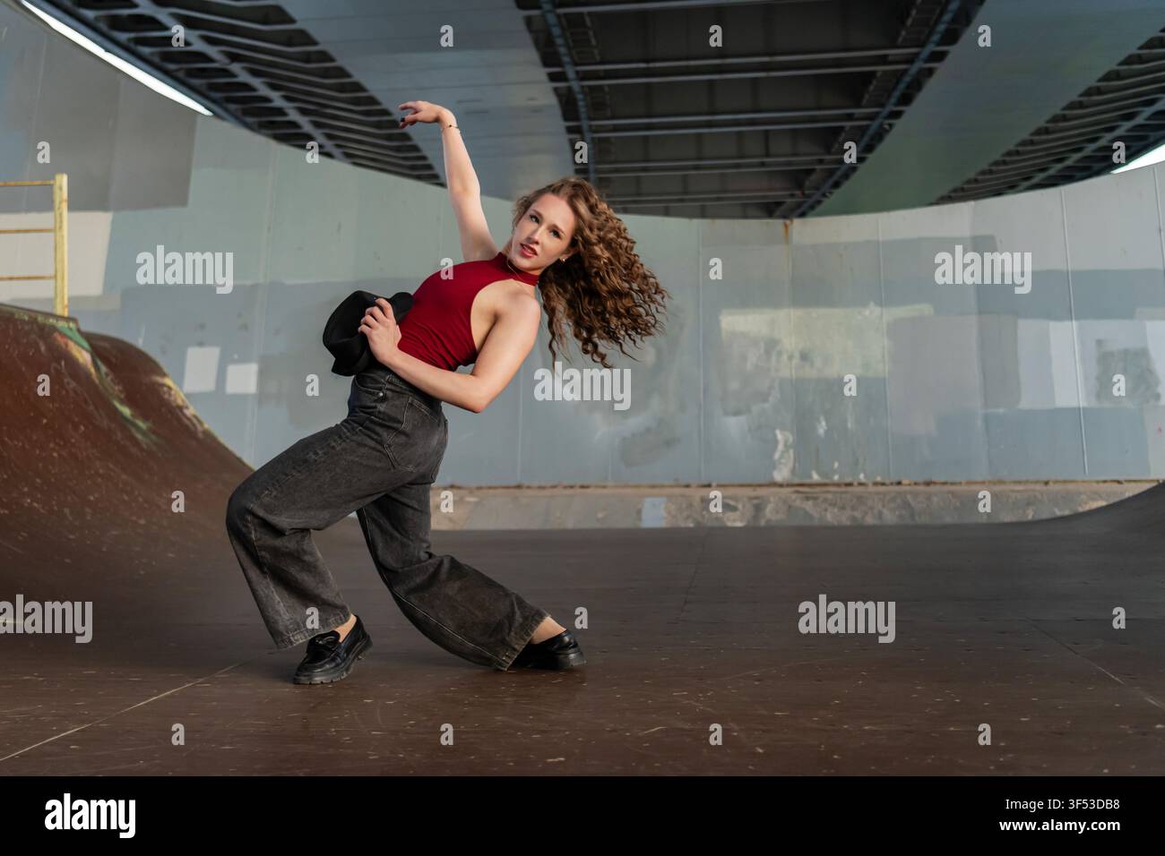 Female dancer striking a dramatic pose under a bridge Stock Photo