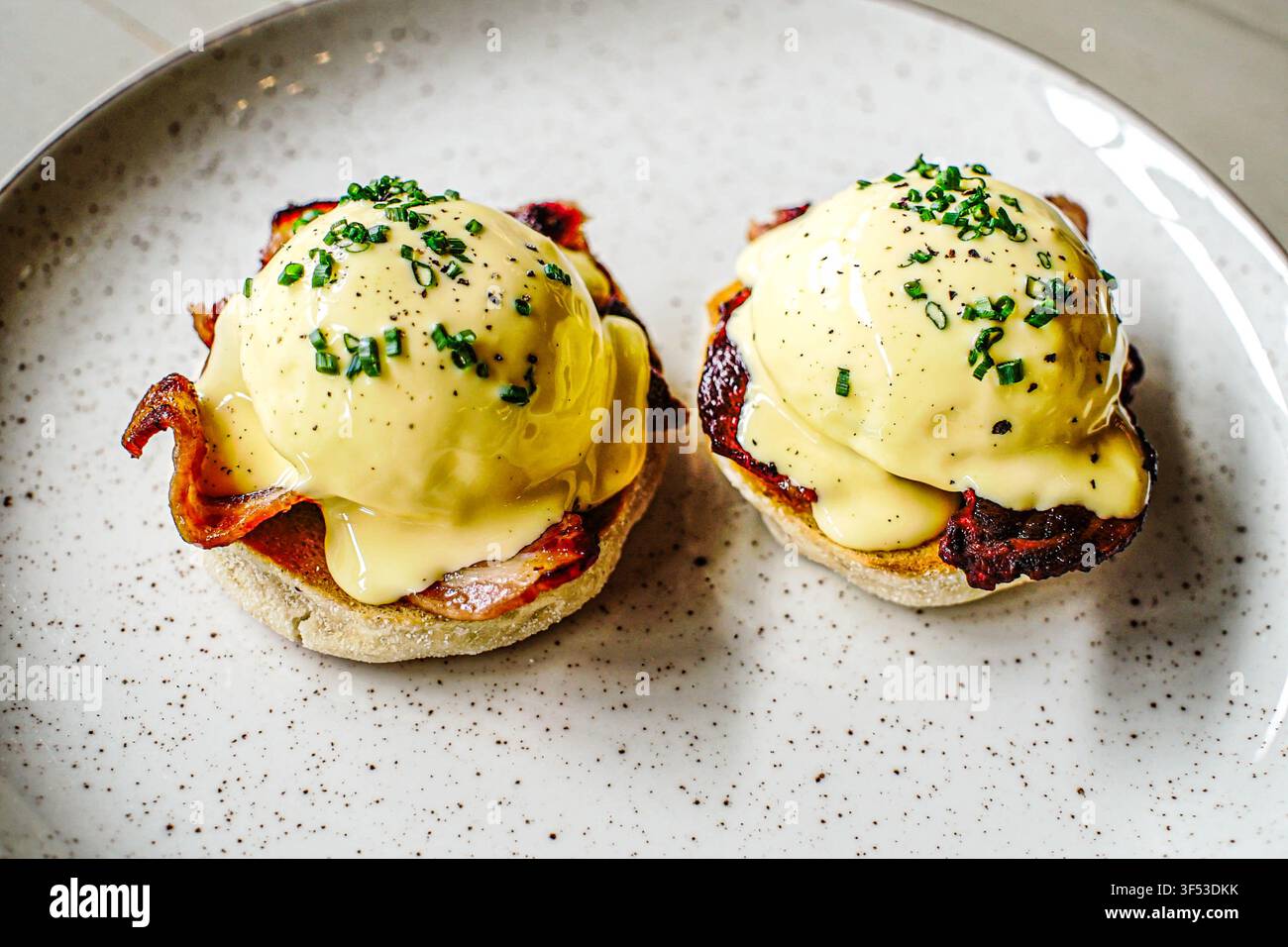Delicious eggs benedict with bacon and chives Stock Photo