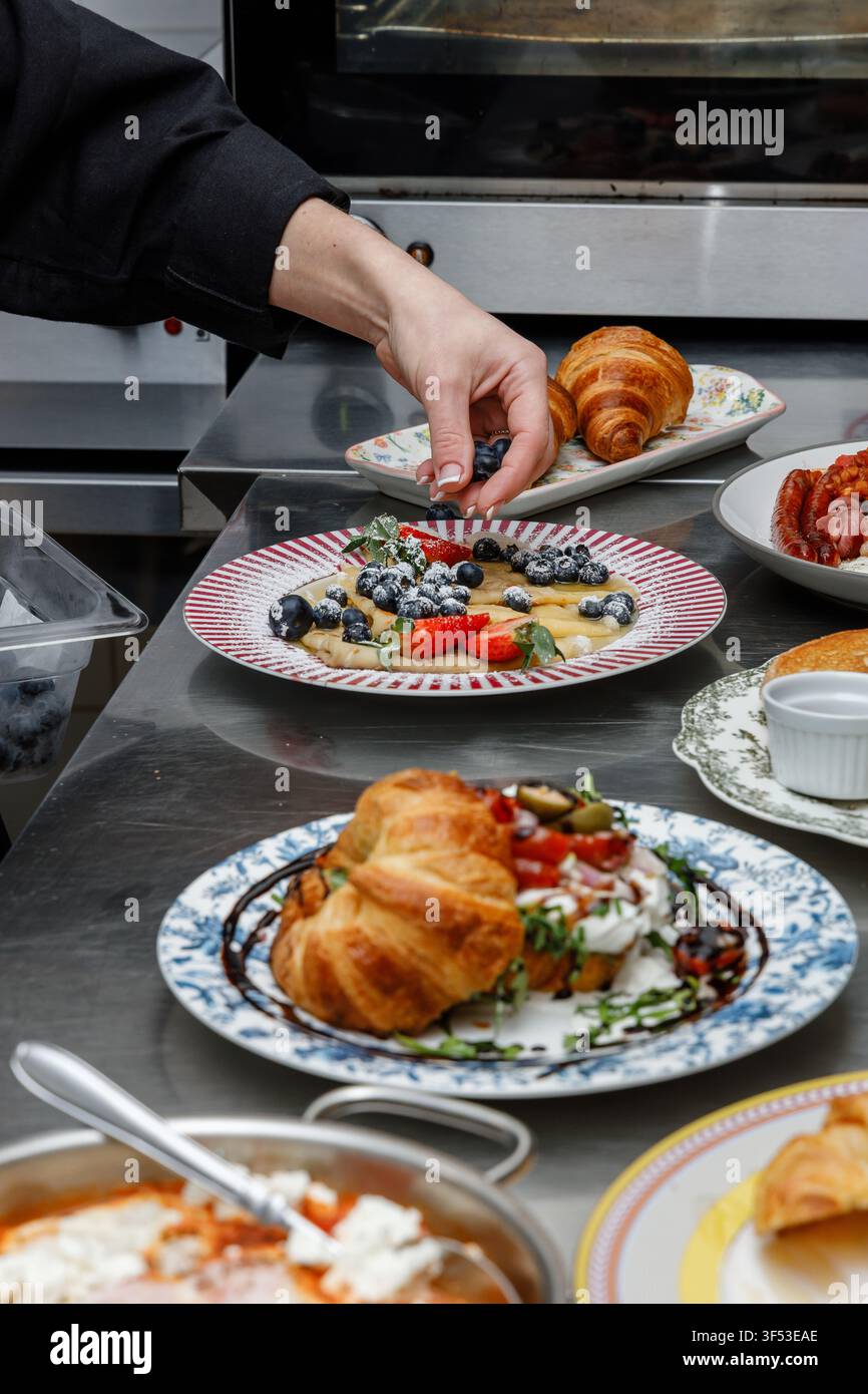 A female chef is preparing breakfasts in a restaurant. Stock Photo