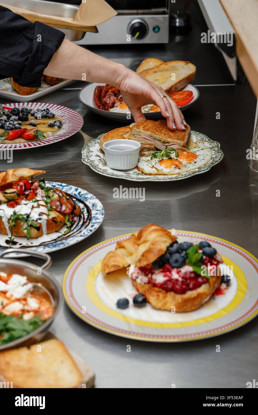 A female chef is preparing breakfasts in a restaurant. Stock Photo