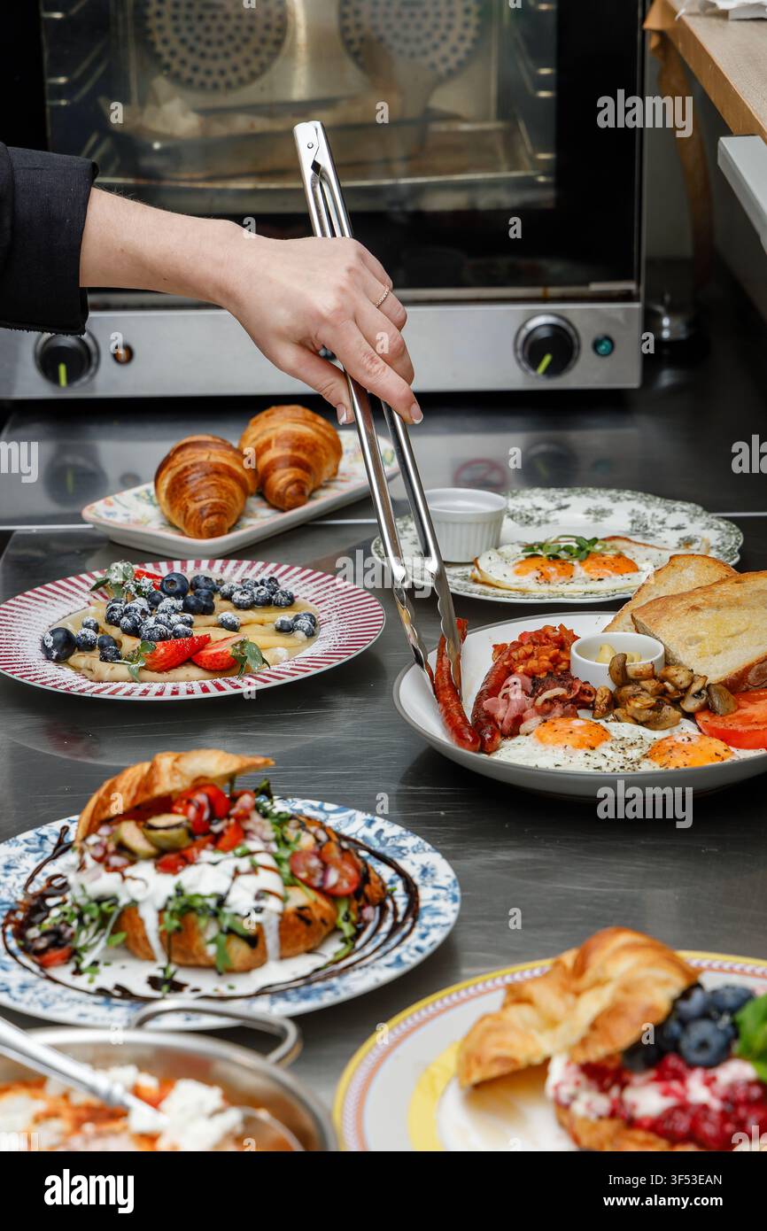 A female chef is preparing breakfasts in a restaurant. Stock Photo