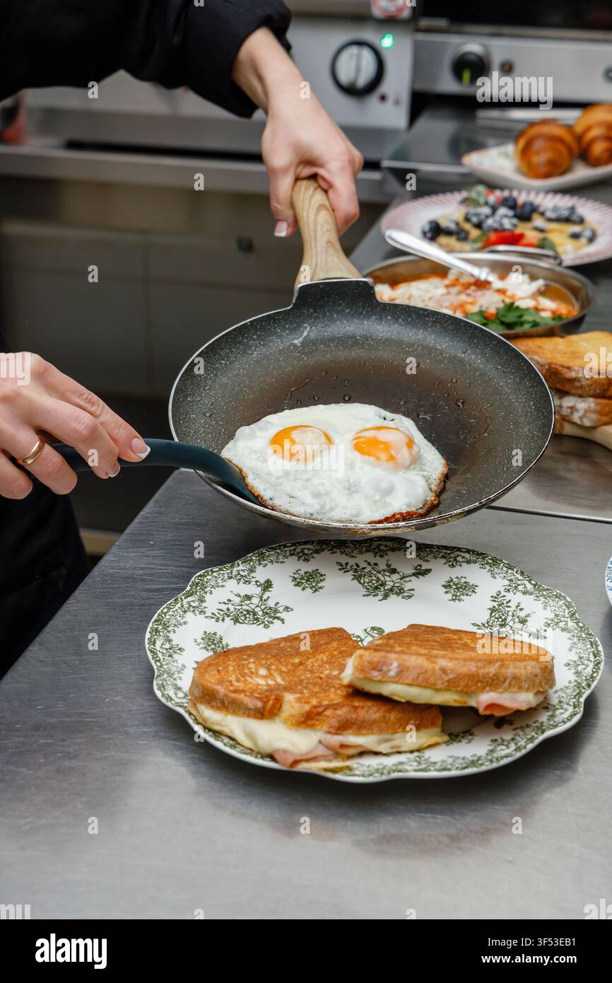 A female chef is preparing breakfasts in a restaurant. Stock Photo