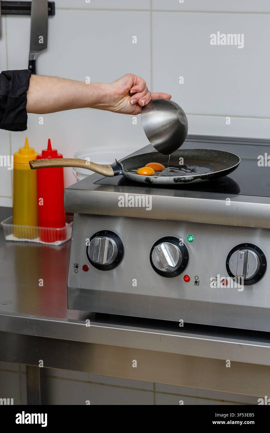 A female chef is preparing breakfasts in a restaurant. Stock Photo