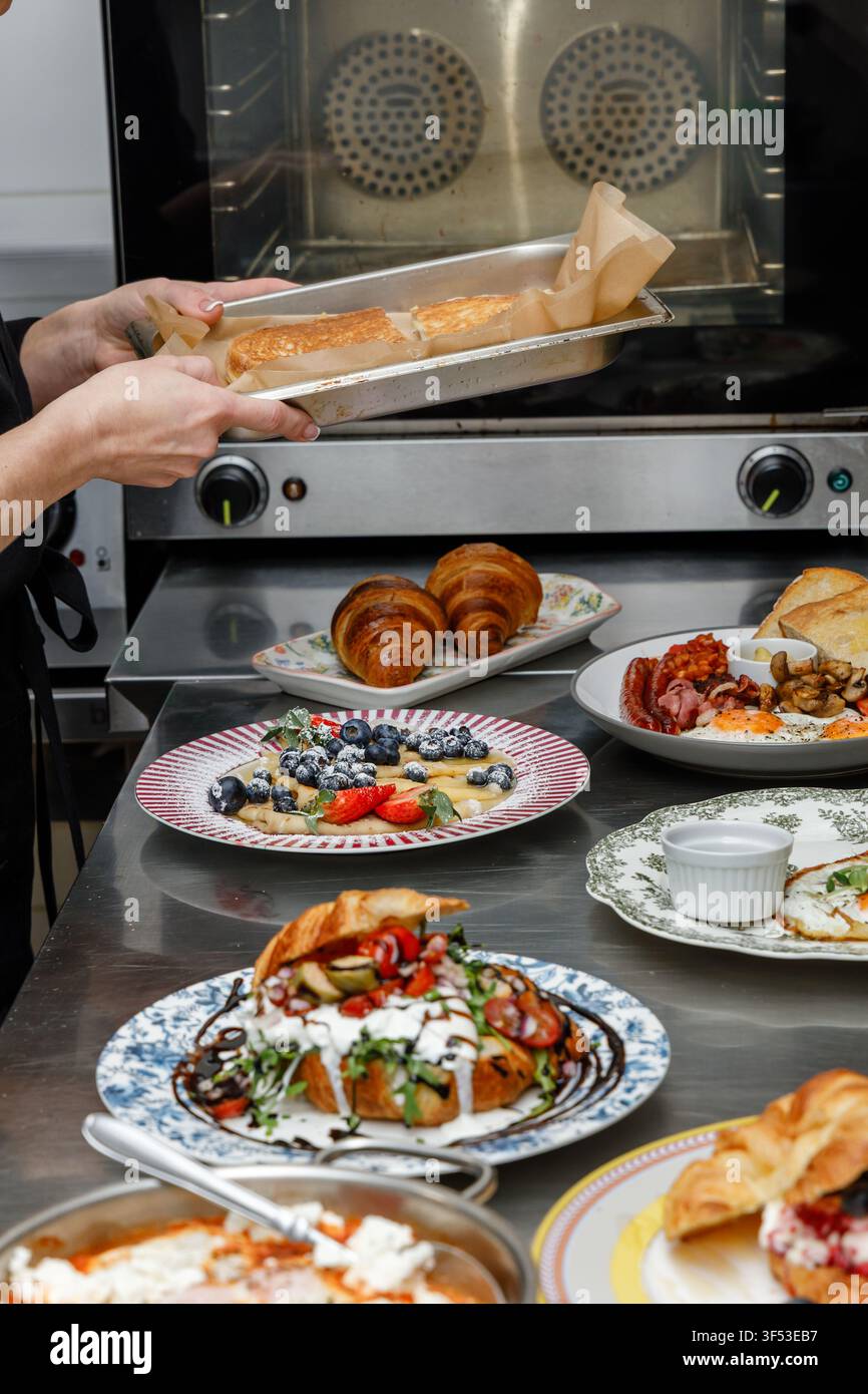 A female chef is preparing breakfasts in a restaurant. Stock Photo