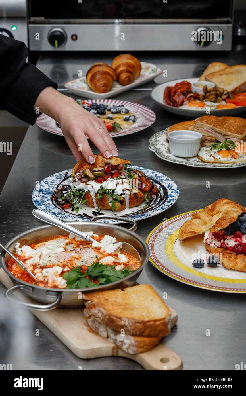 A female chef is preparing breakfasts in a restaurant. Stock Photo