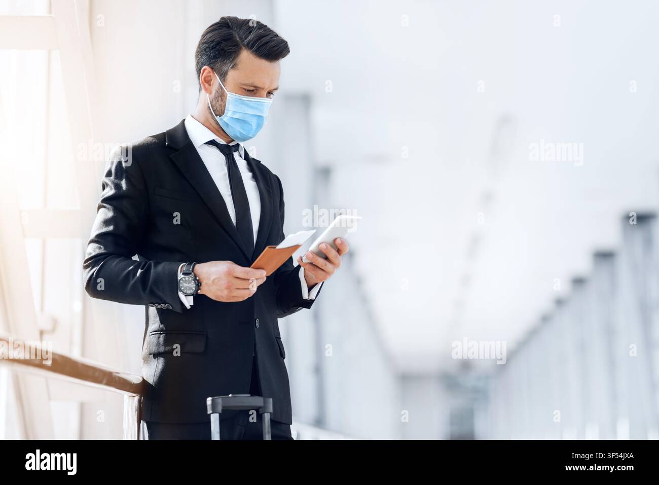 Entrepreneur in face mask using phone while waiting for flight Stock Photo