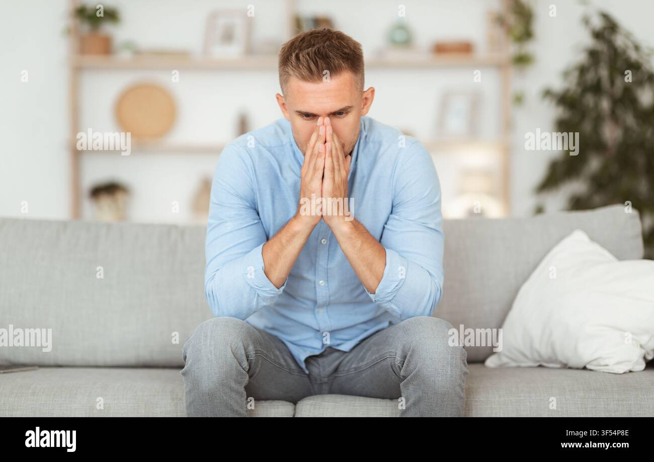 Depressed sad man sitting on couch, thinking about problems Stock Photo