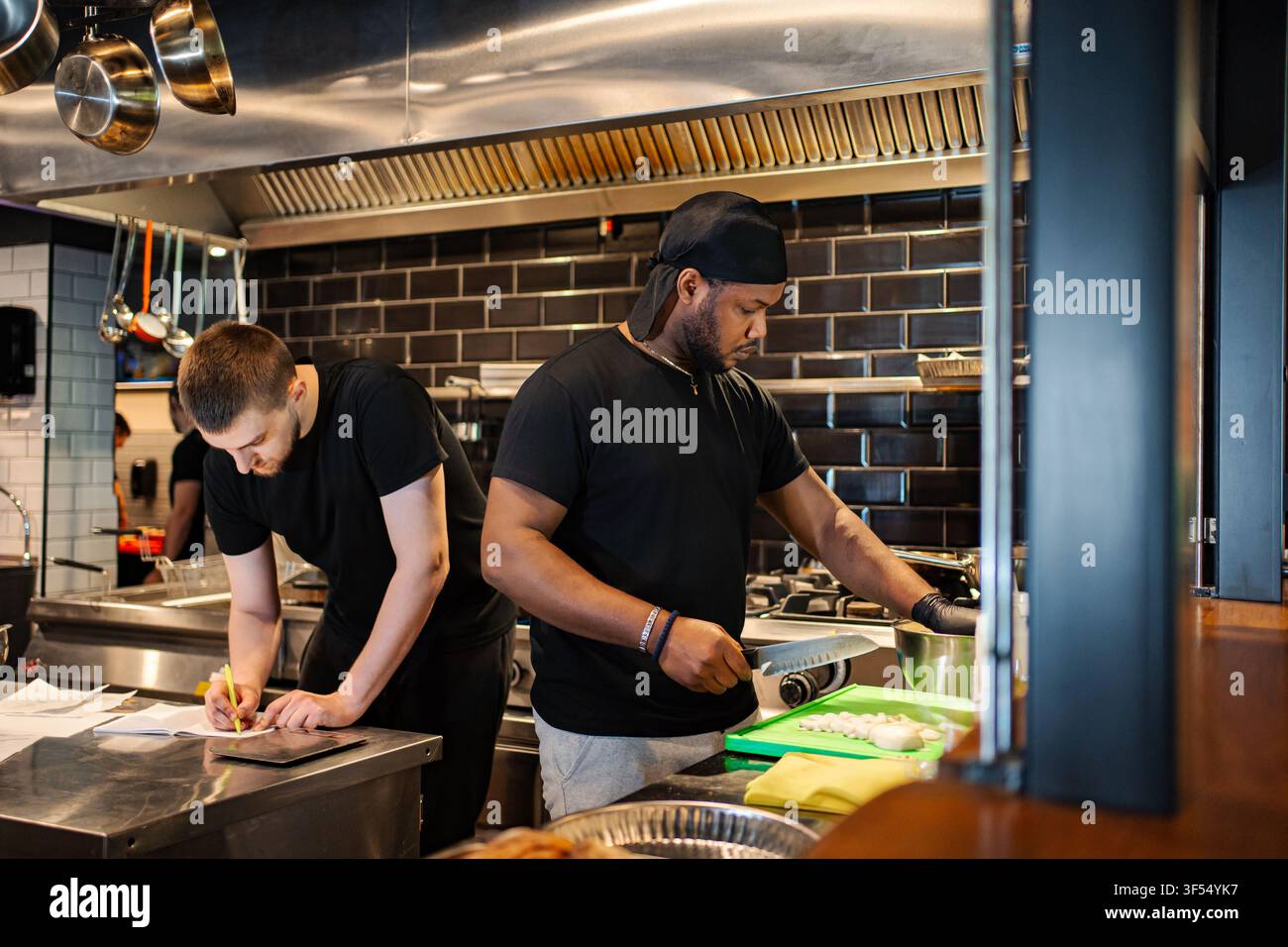Chefs working in professional restaurant kitchen preparing food Stock Photo