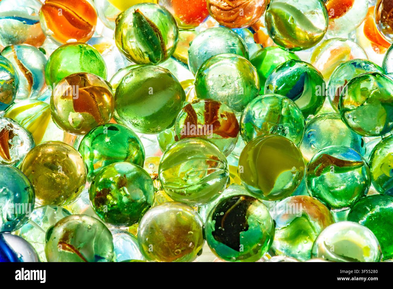 Glass marbles in various colors and patterns forming a translucent, textured background Stock Photo