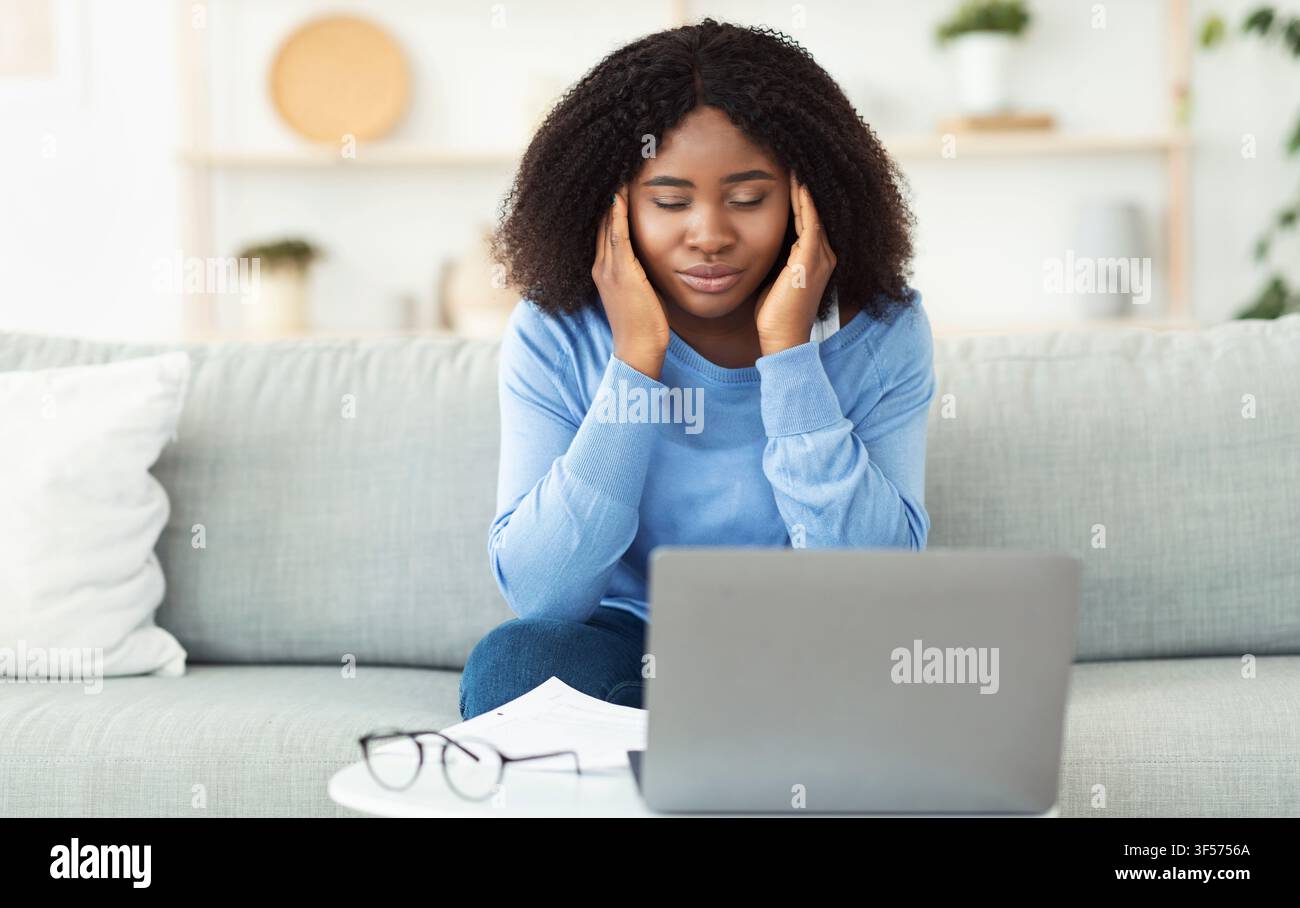 Tired black lady touching and massaging temples Stock Photo