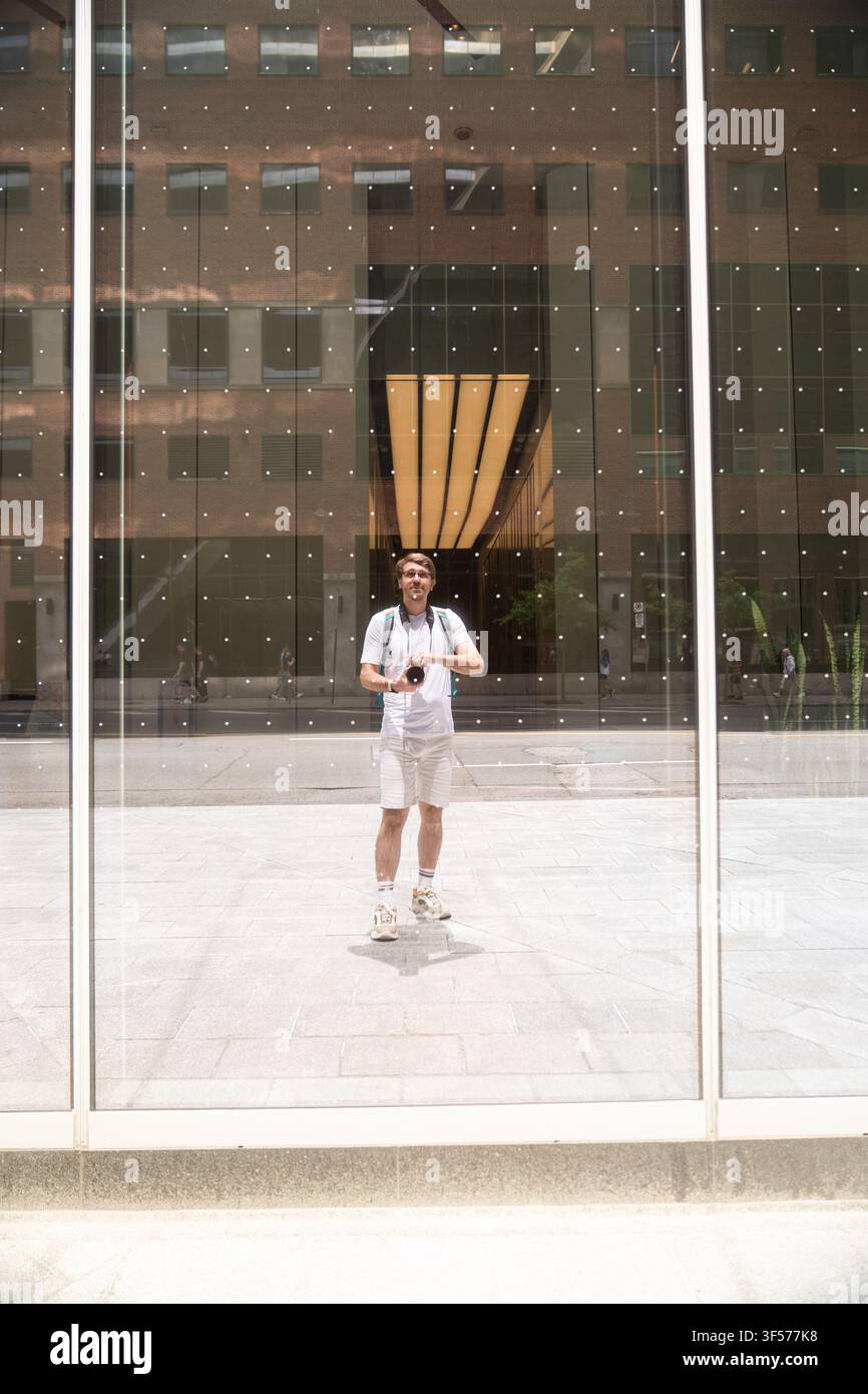 Man taking self-portrait reflection in glass building facade Stock Photo