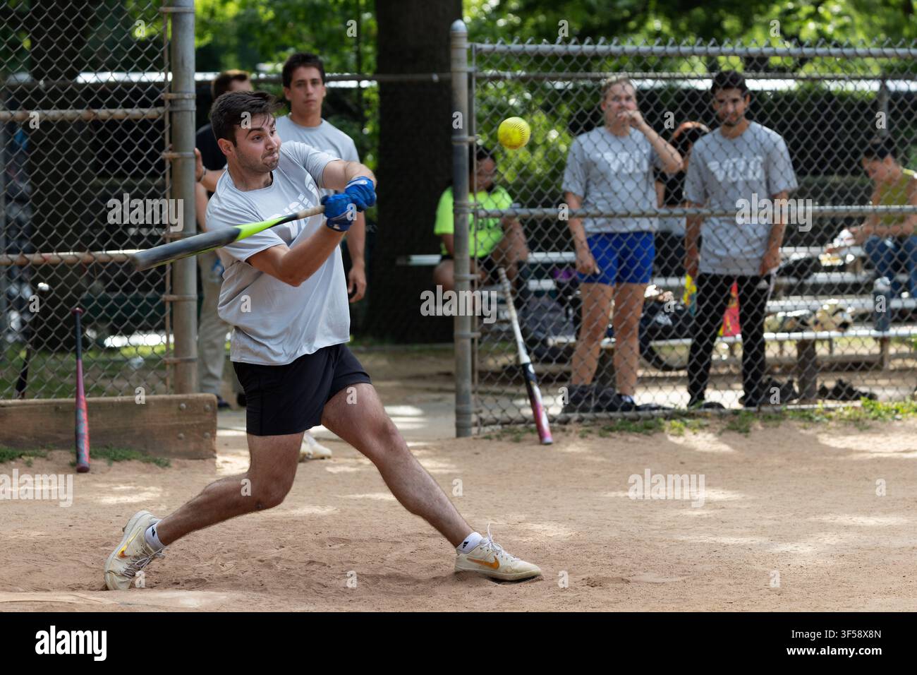 A recreational softball player swings at a pitch on a field in Boston Common, Boston, Massachusetts. Stock Photo