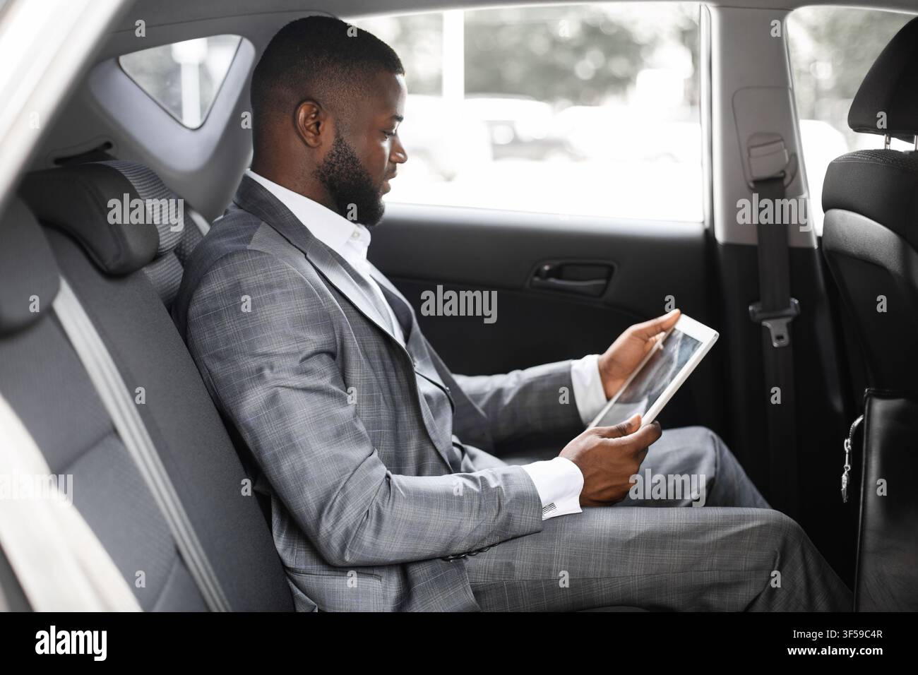Concentrated black guy manager using digital tablet in car Stock Photo