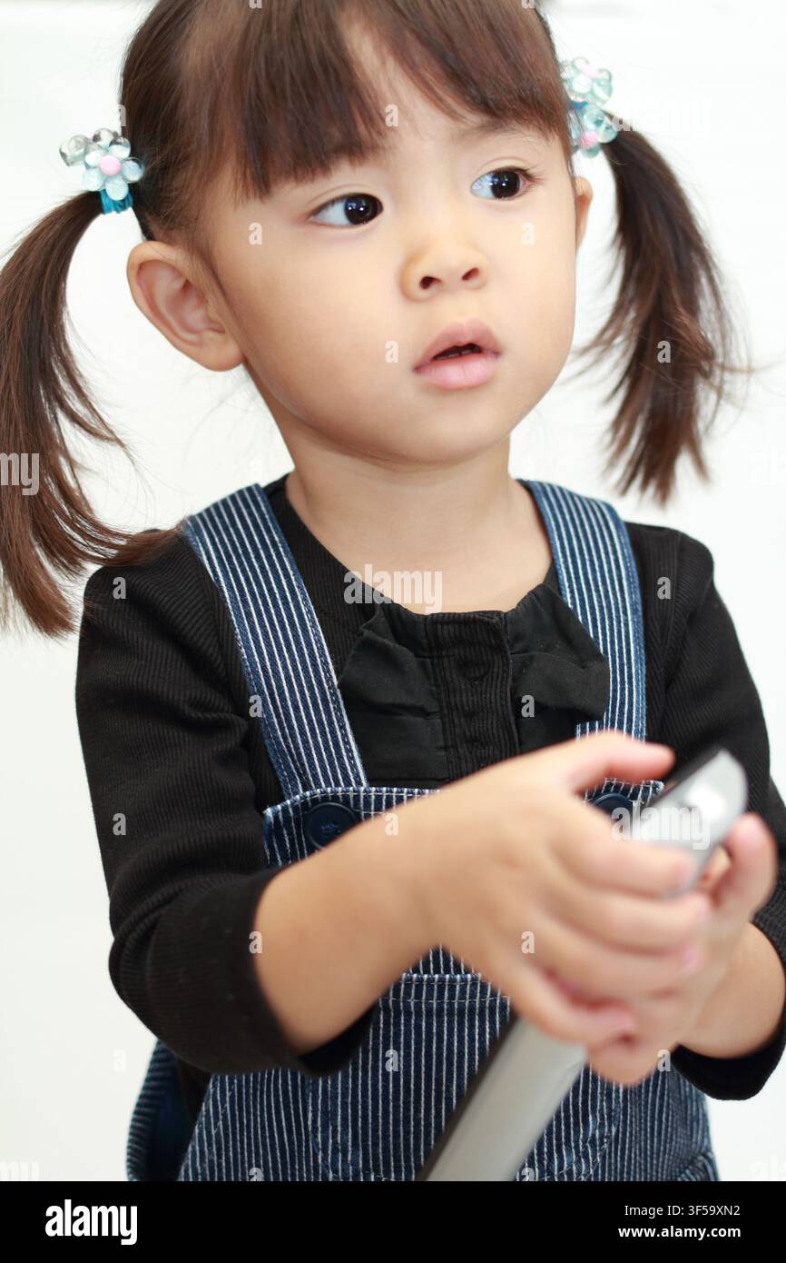 Japanese girl using remote controller (3 years old) Stock Photo