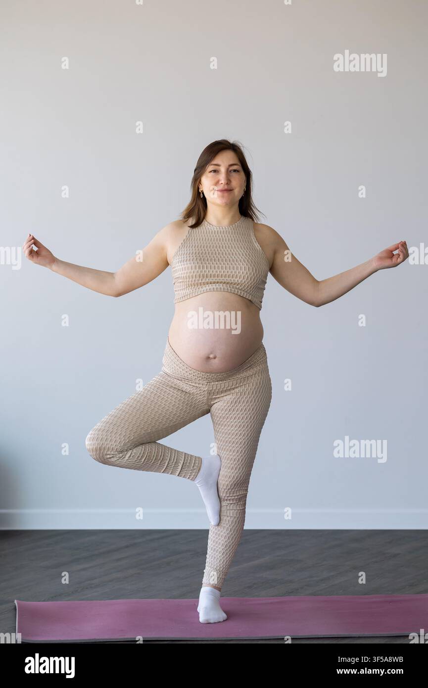 Pregnant woman practicing yoga tree pose for wellness Stock Photo