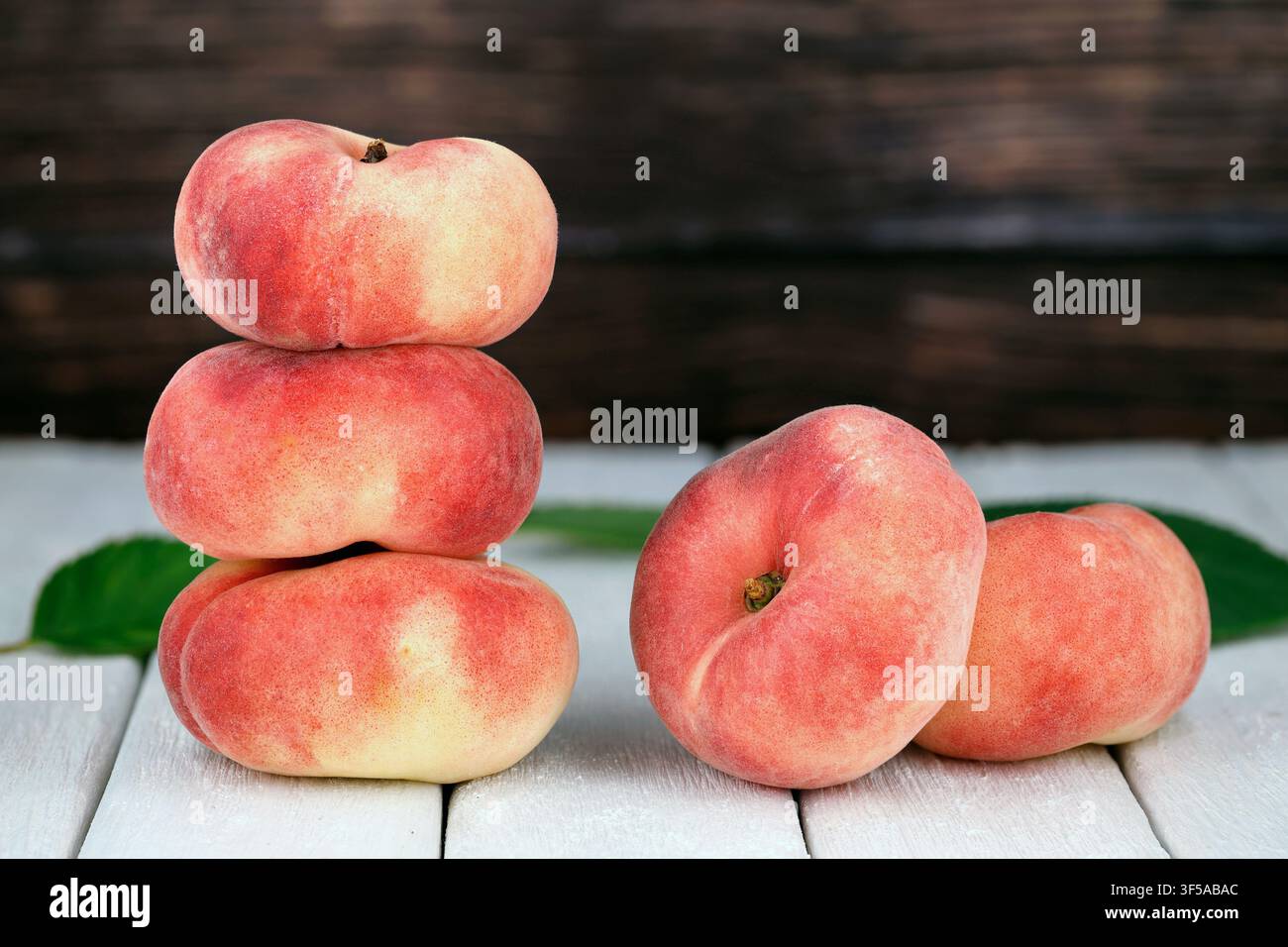 Fresh Flat Peaches, Saturn Peaches, Prunus persica var. platycarpa, on White Wooden Table with Rustic Background Stock Photo