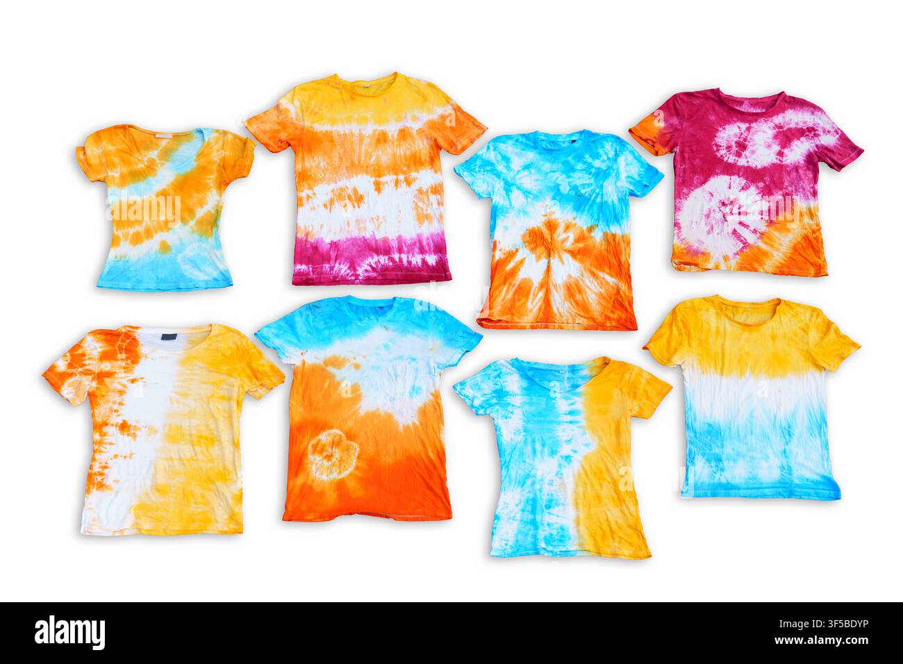 Colorful hand-dyed tie dye t-shirts with vibrant spiral and striped patterns displayed flat lay on a dark asphalt background during a summer creative Stock Photo