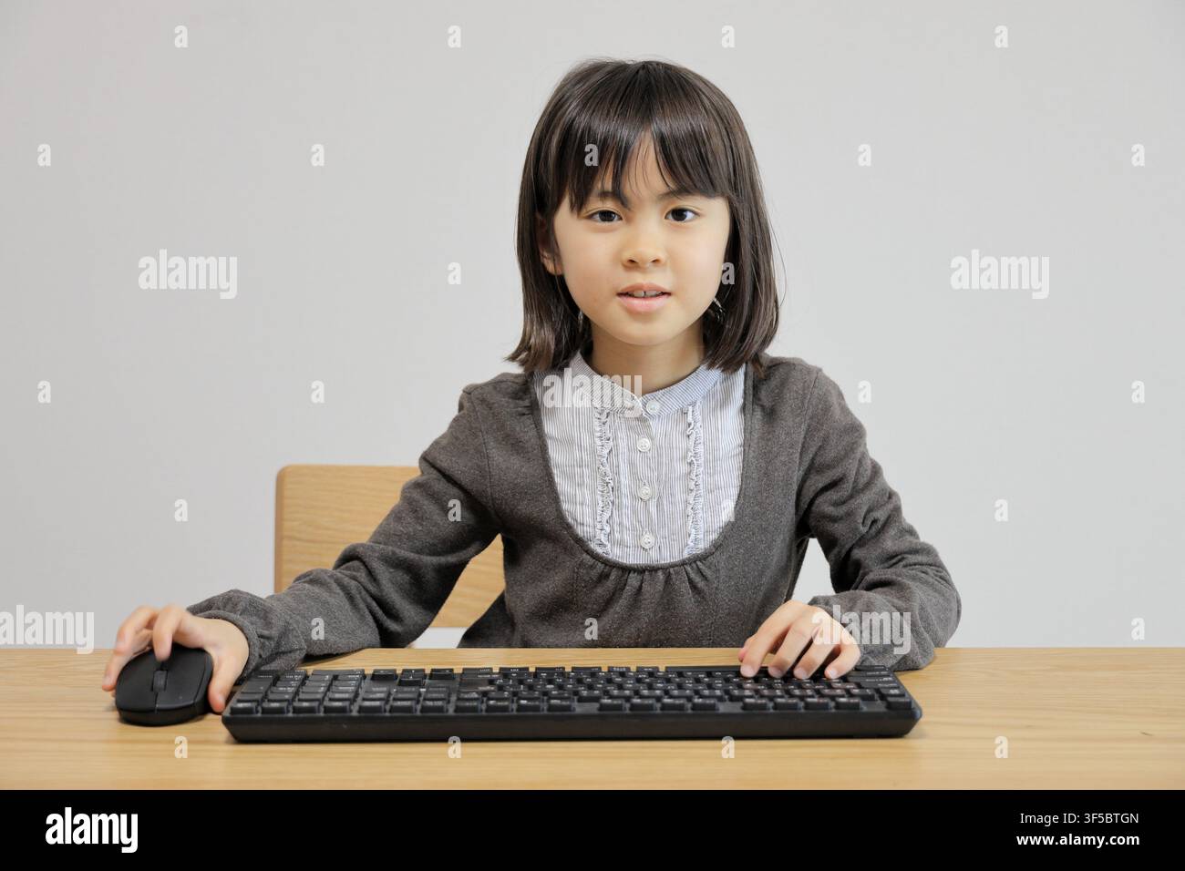 Japanese student girl using PC mouse (8 years old) Stock Photo