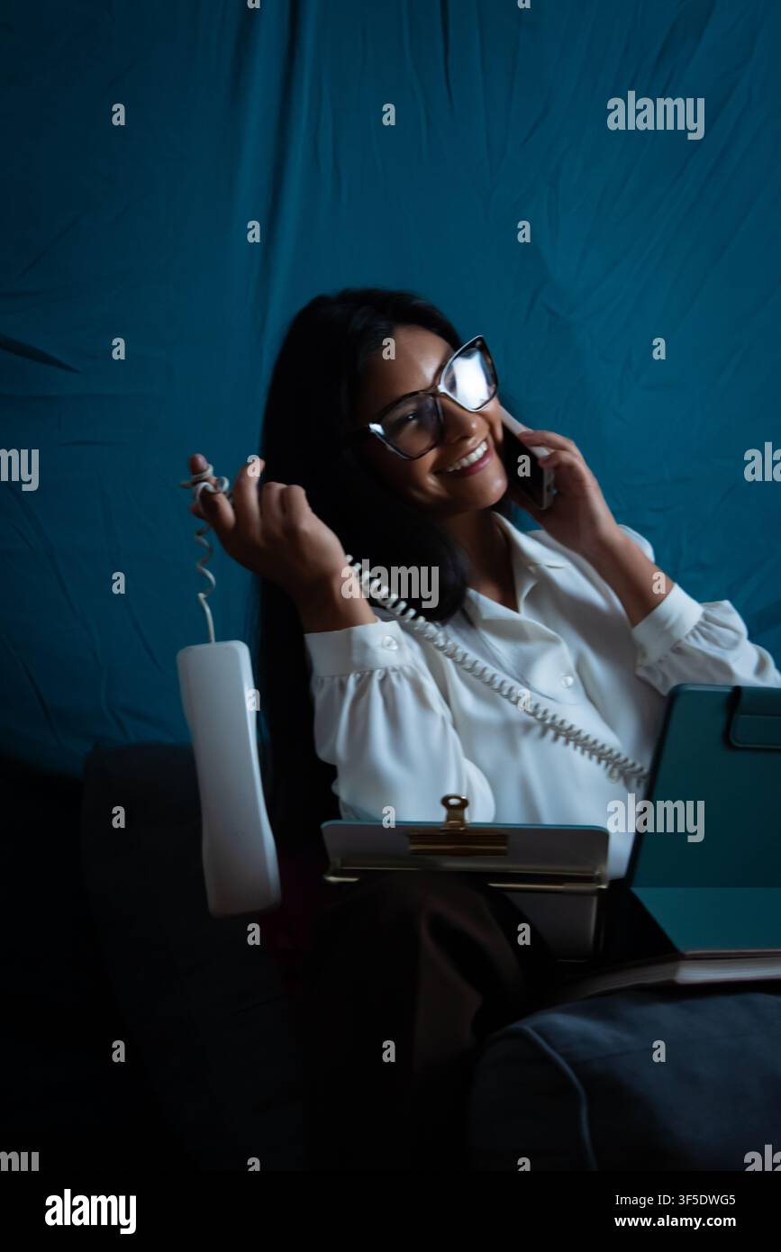 Woman multi-tasking talking on modern and retro phones Stock Photo