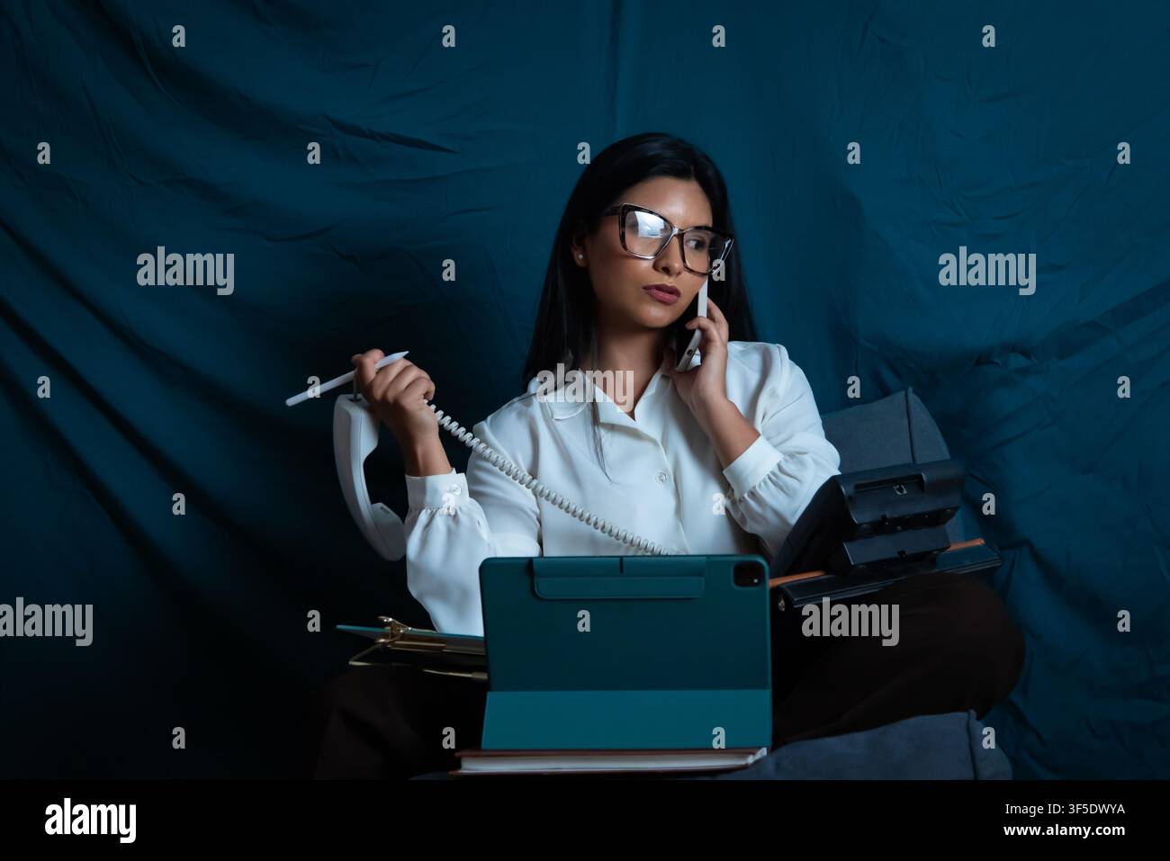 Woman multitasking, managing multiple calls and devices Stock Photo