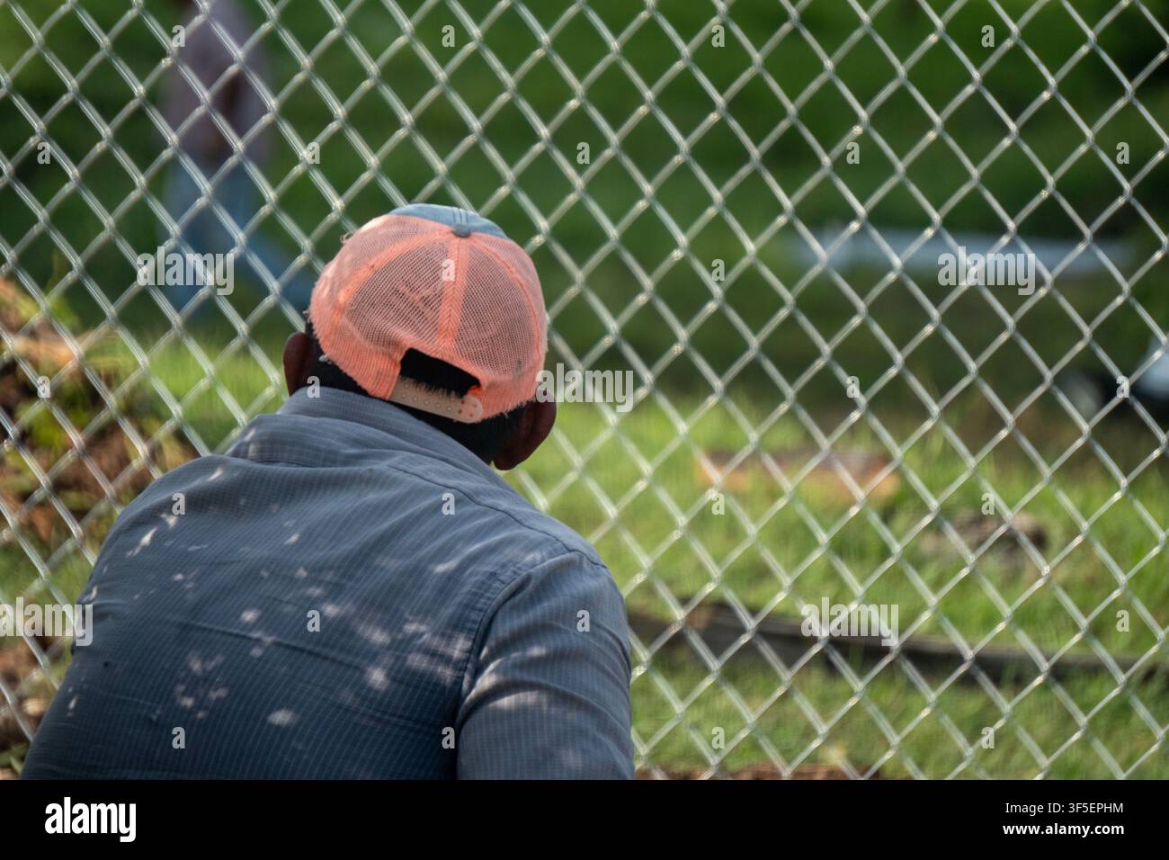 Worker waits behind a security fence Stock Photo