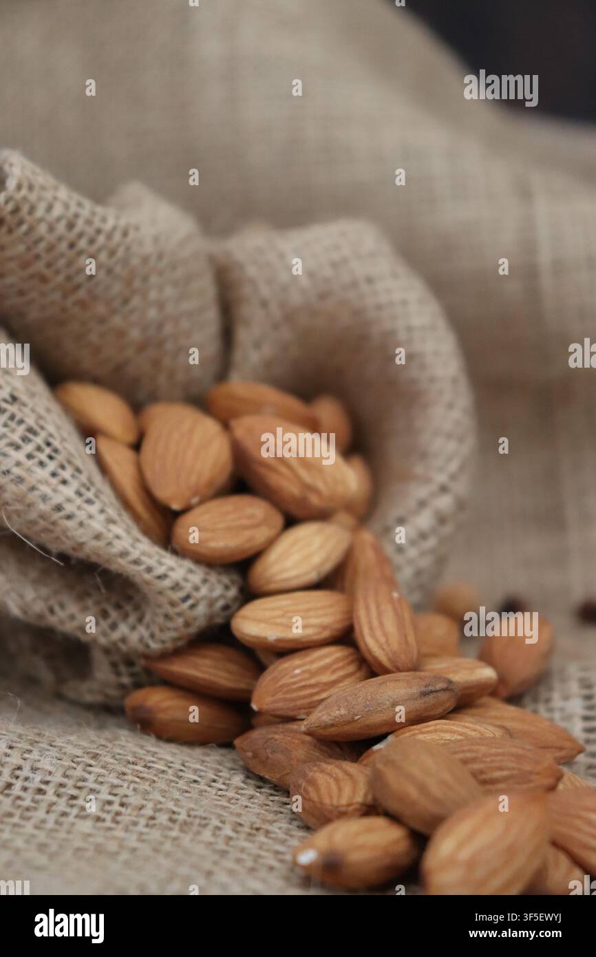 spilled almonds in burlap bag Stock Photo