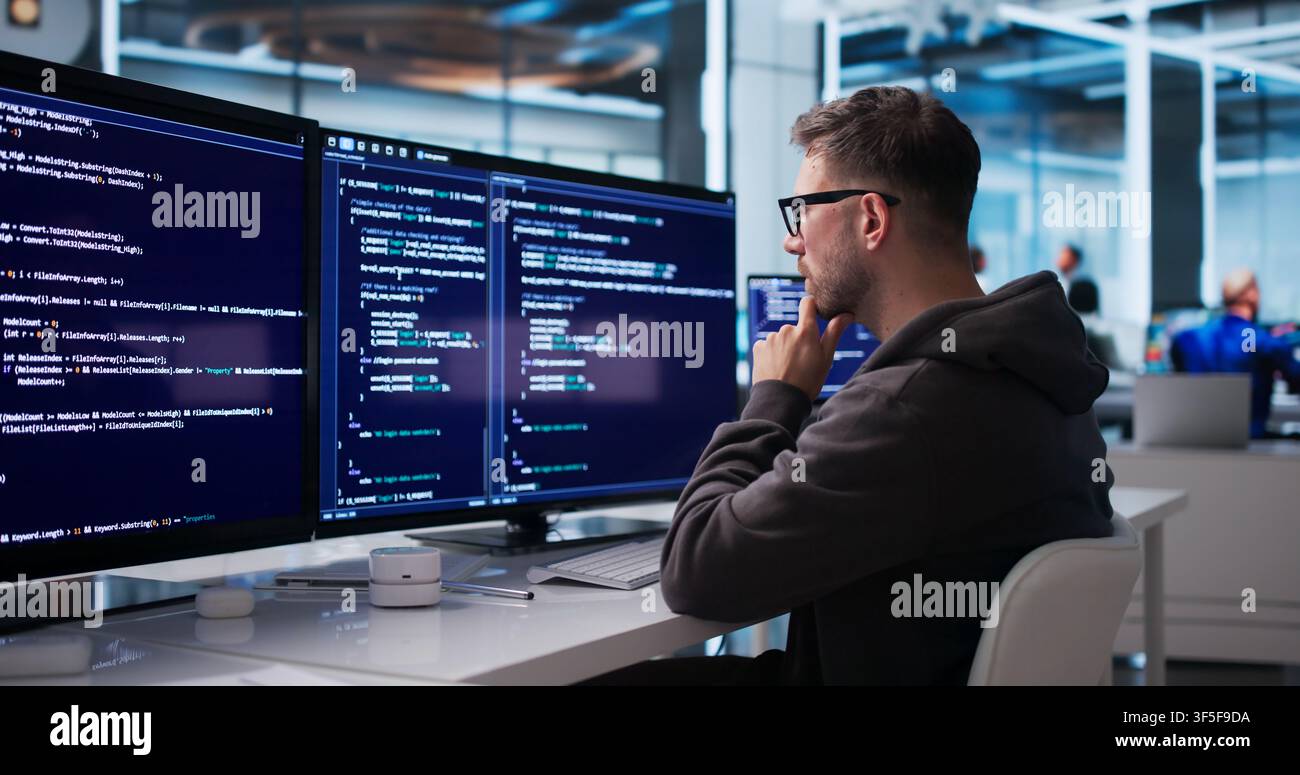 Young Software Engineer Coding Secure Business Platform At Modern Office Desk. Stock Photo