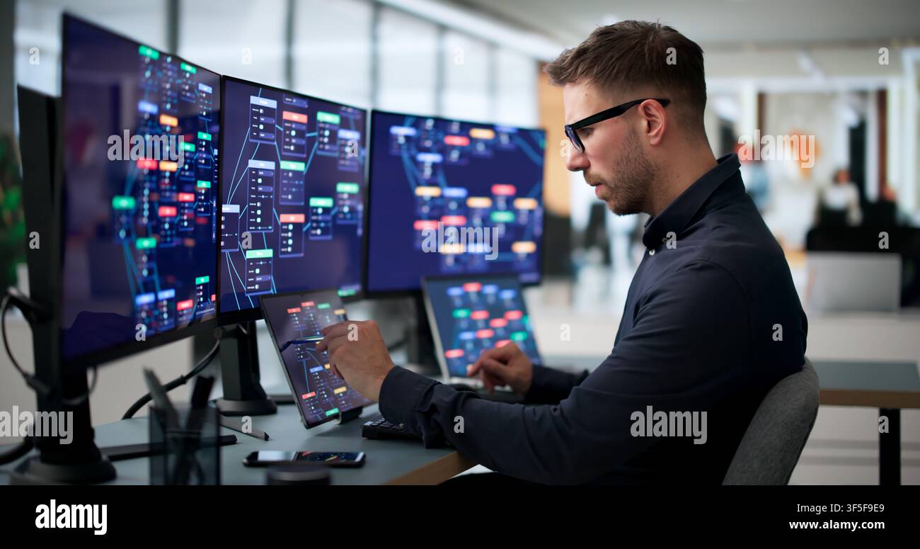 Young Man Uses Laptop And Tablet To Build Digital Business Workflows Rapidly. Stock Photo