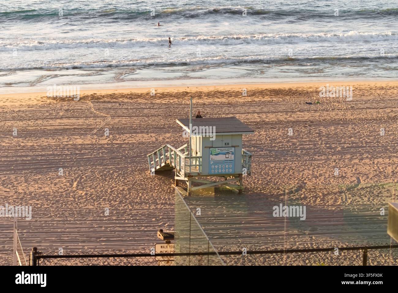 Lifeguard tower on sandy beach at sunset with gentle waves rolling in behind it. Stock Photo