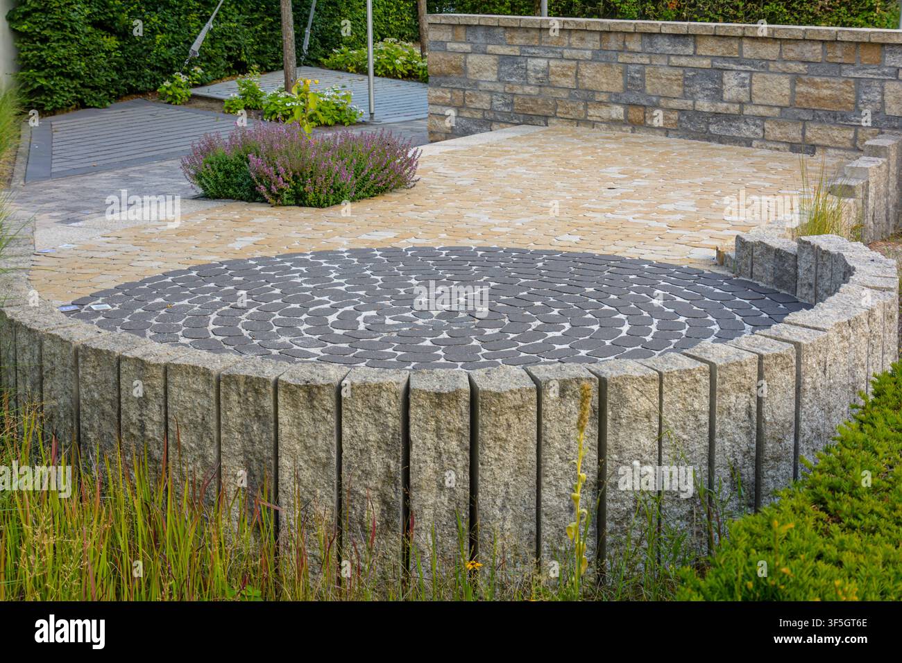 Round paved patio with stone palisades and decorative paving in Coesfeld, Germany Stock Photo