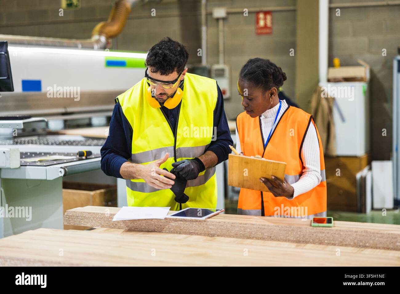 Multiracial workers collaborating in wood processing factory Stock Photo