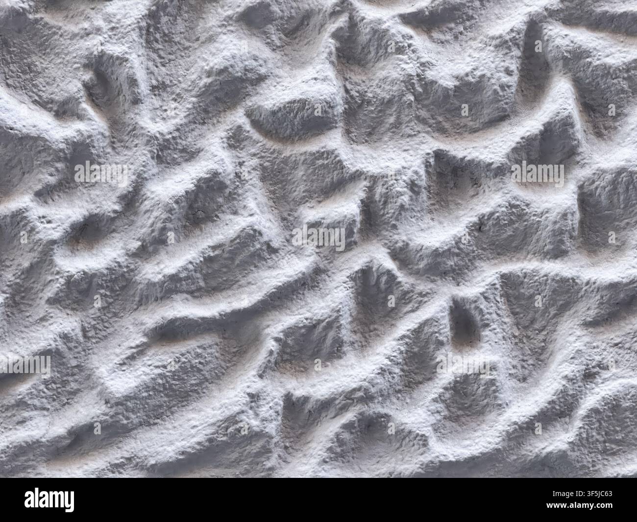 Abstract close-up of uneven white powder with ridges, hollows, and soft shadows, creating a textured monochrome background resembling snowy terrain or Stock Photo
