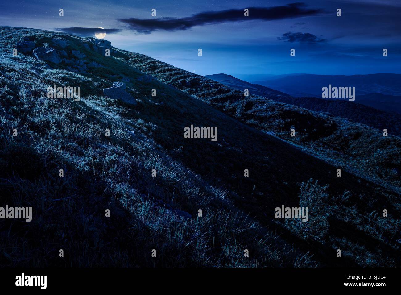 mountain landscape in summer at night. mysterious outdoor scenery of carpathian mountains. full moon over grassy slopes with rocks. fantasy image for Stock Photo