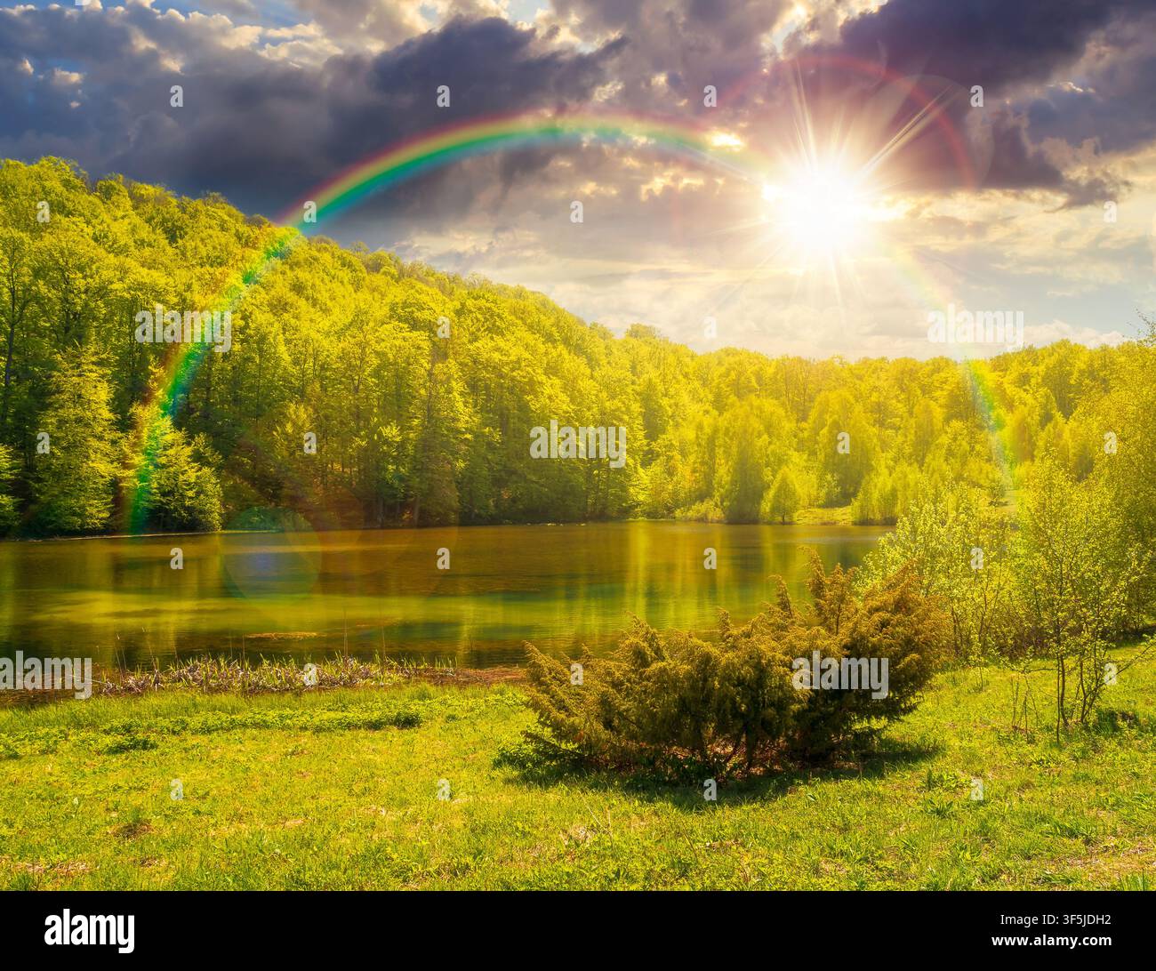 sunset over landscape by the lake. deciduous forest near the glacial lake. view of primeval forest of carpathian mountains in spring. cloudy sky. hiki Stock Photo