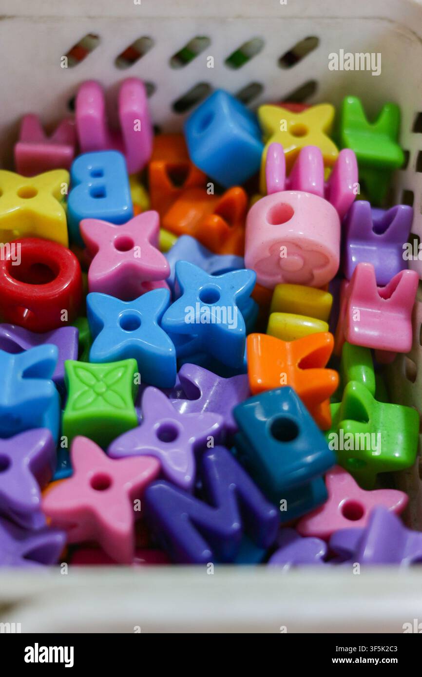 Colorful alphabet and star shaped plastic beads stored in a container for children's crafts, creative play, letter learning and educational activities Stock Photo