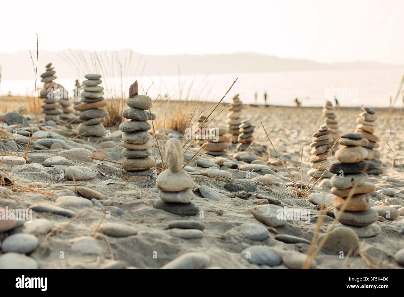 Balanced stone cairns on a sandy beach at sunset Stock Photo