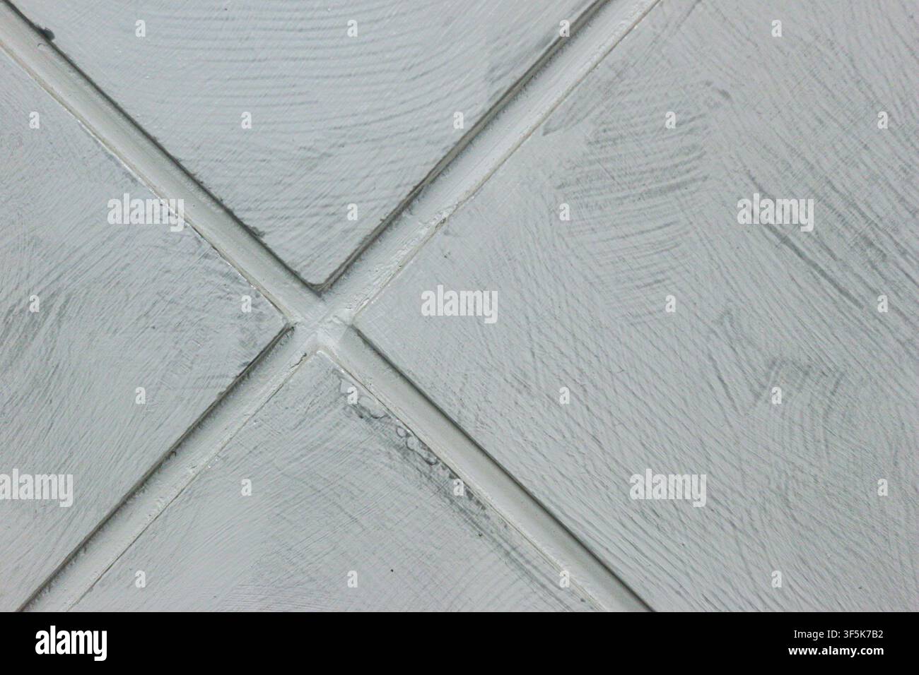 Close up of a pale grey textured wall surface with diagonal grooves forming a crossing diamond pattern, abstract background. Stock Photo