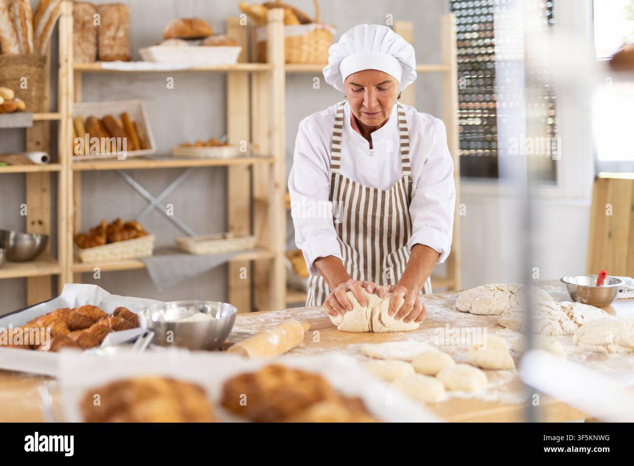Elderly female baker working diligently in a bakery Stock Photo