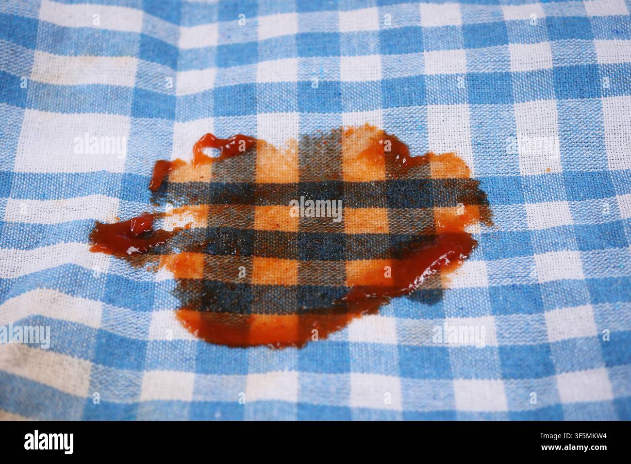 Stain on a checkered cloth in a kitchen setting Stock Photo