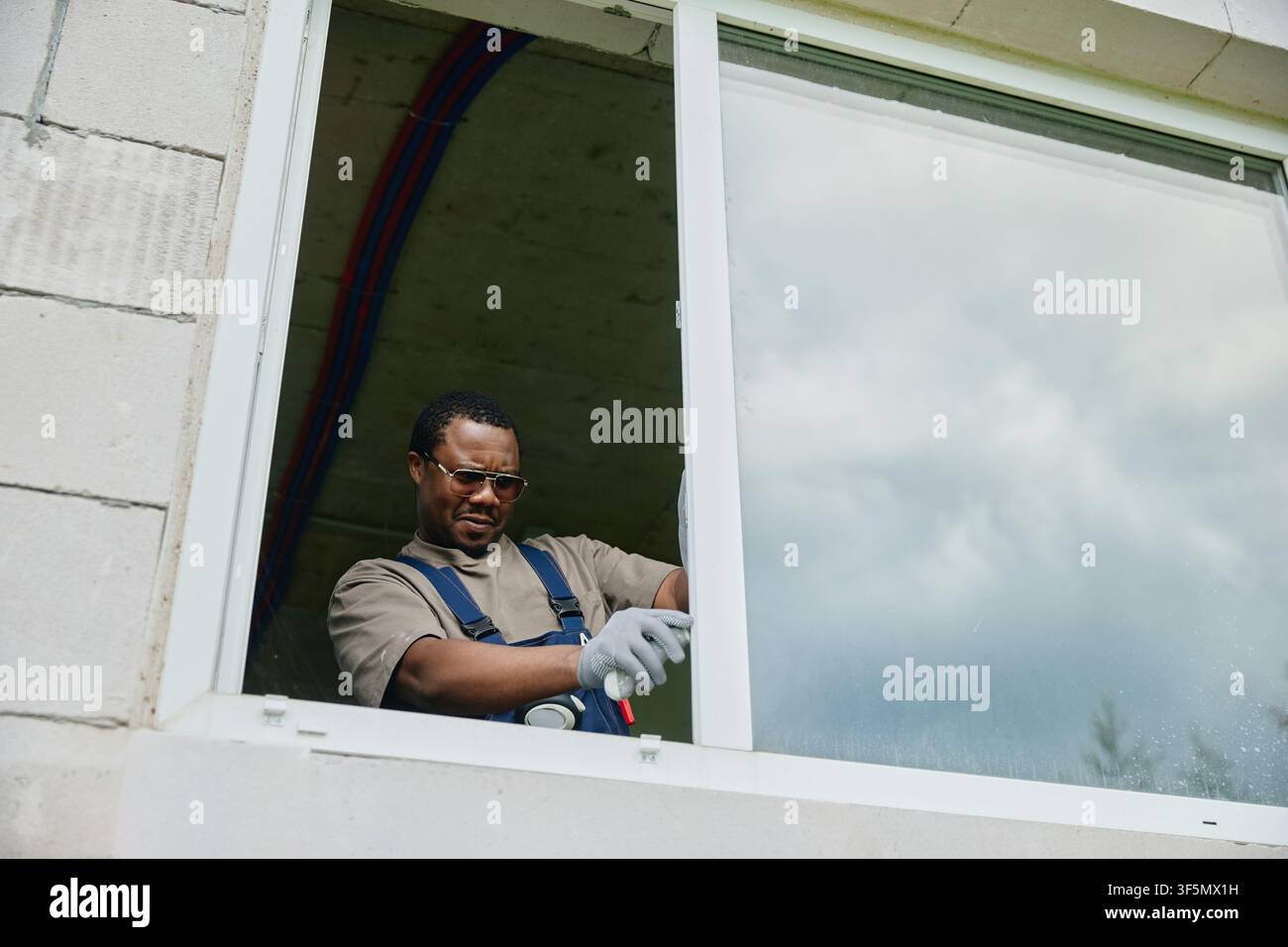 Black Man Installing New Window during House Renovation Stock Photo