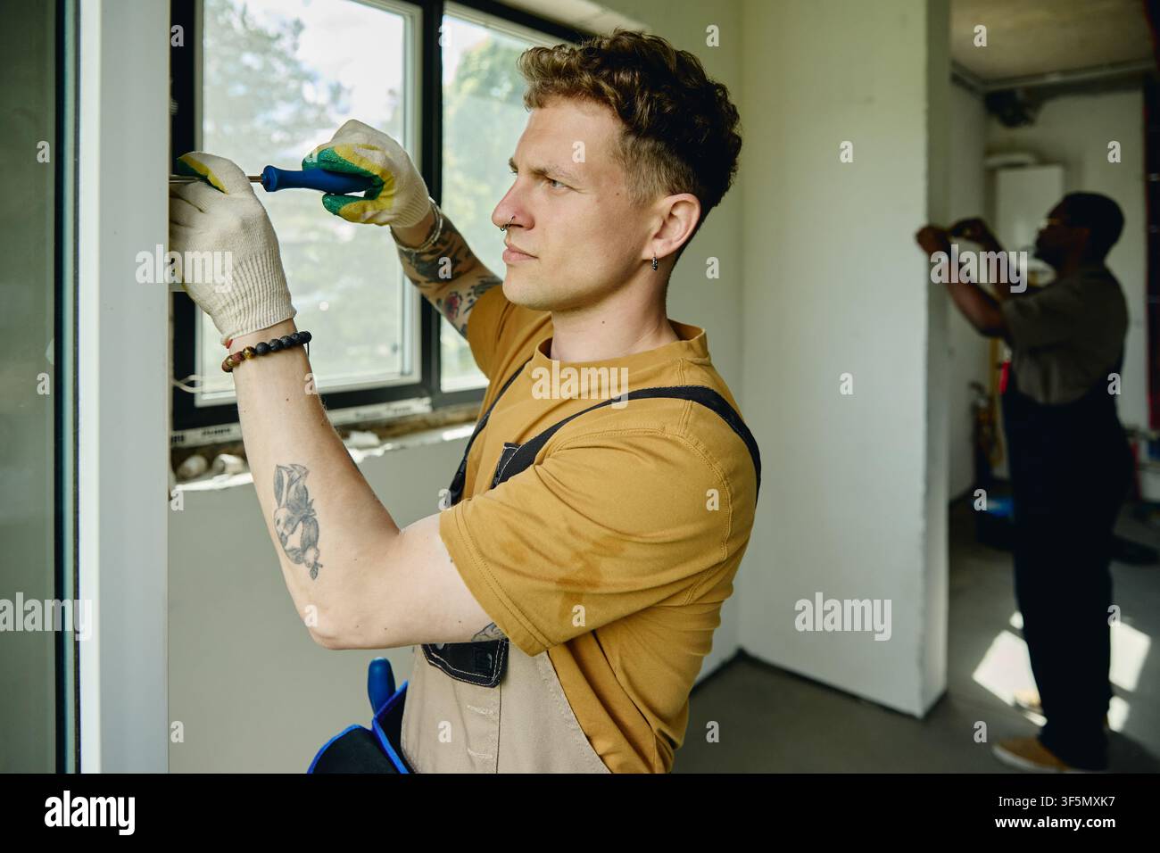 Man Installing Window Frame during House Renovation Stock Photo