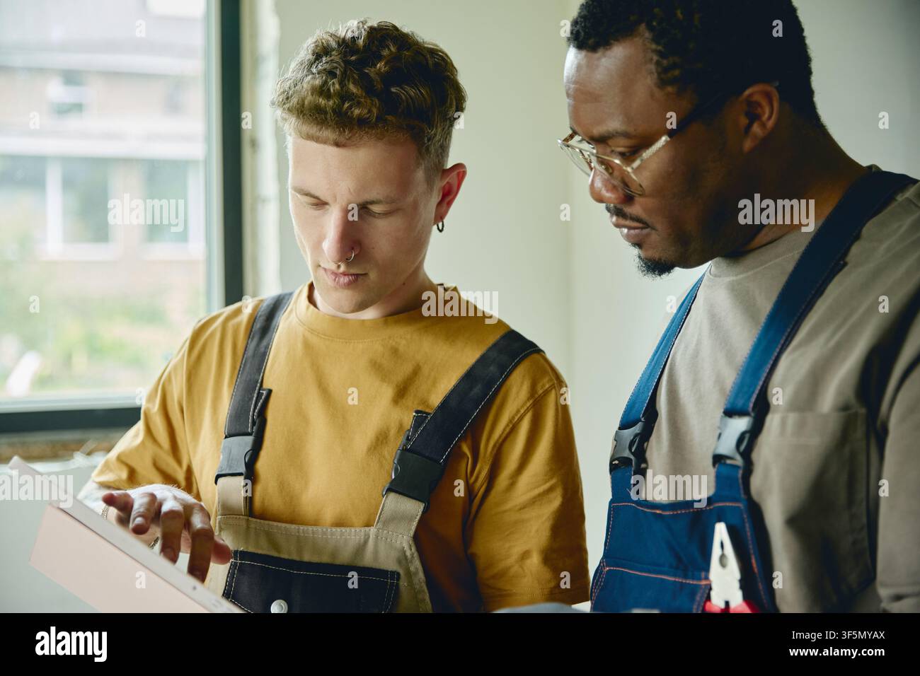 Man and Black Man Planning House Renovation Using Digital Tablet Stock Photo