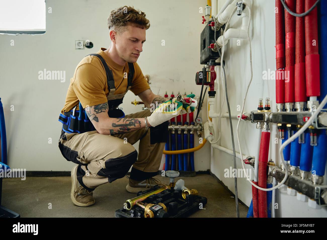 Man Installing Heating System during House Renovation Stock Photo