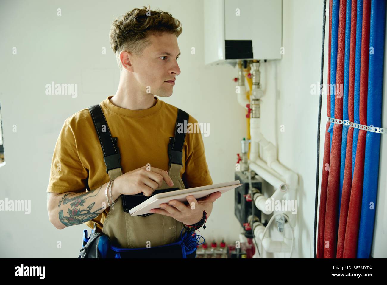 Man Repairing Heating System and Using Tablet during House Renovation Stock Photo