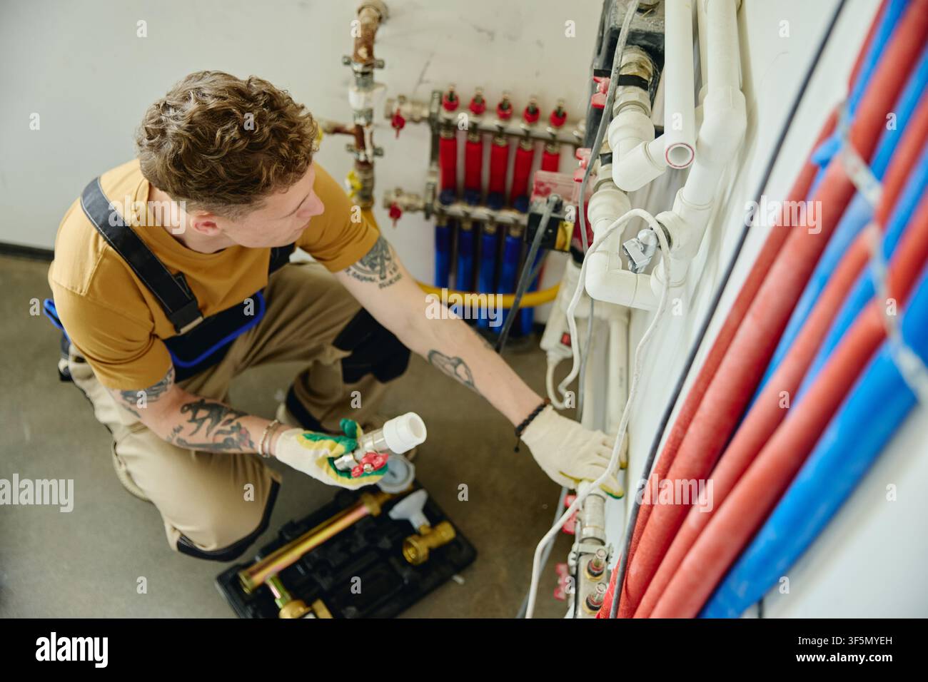 Man Installing Heating Pipes during House Renovation Stock Photo