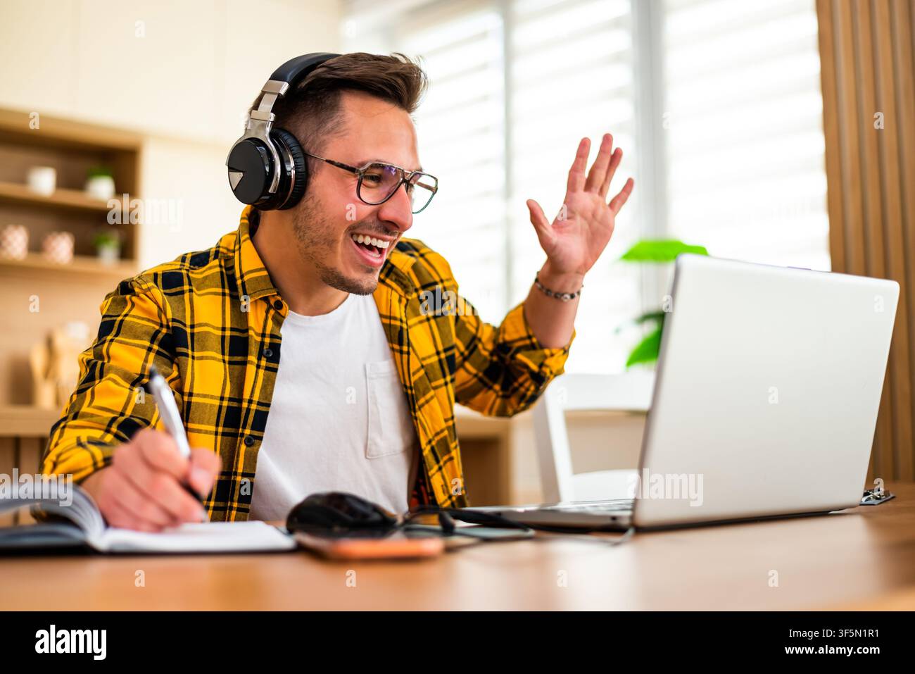 Young man is using laptop for online communication while working at home. Stock Photo
