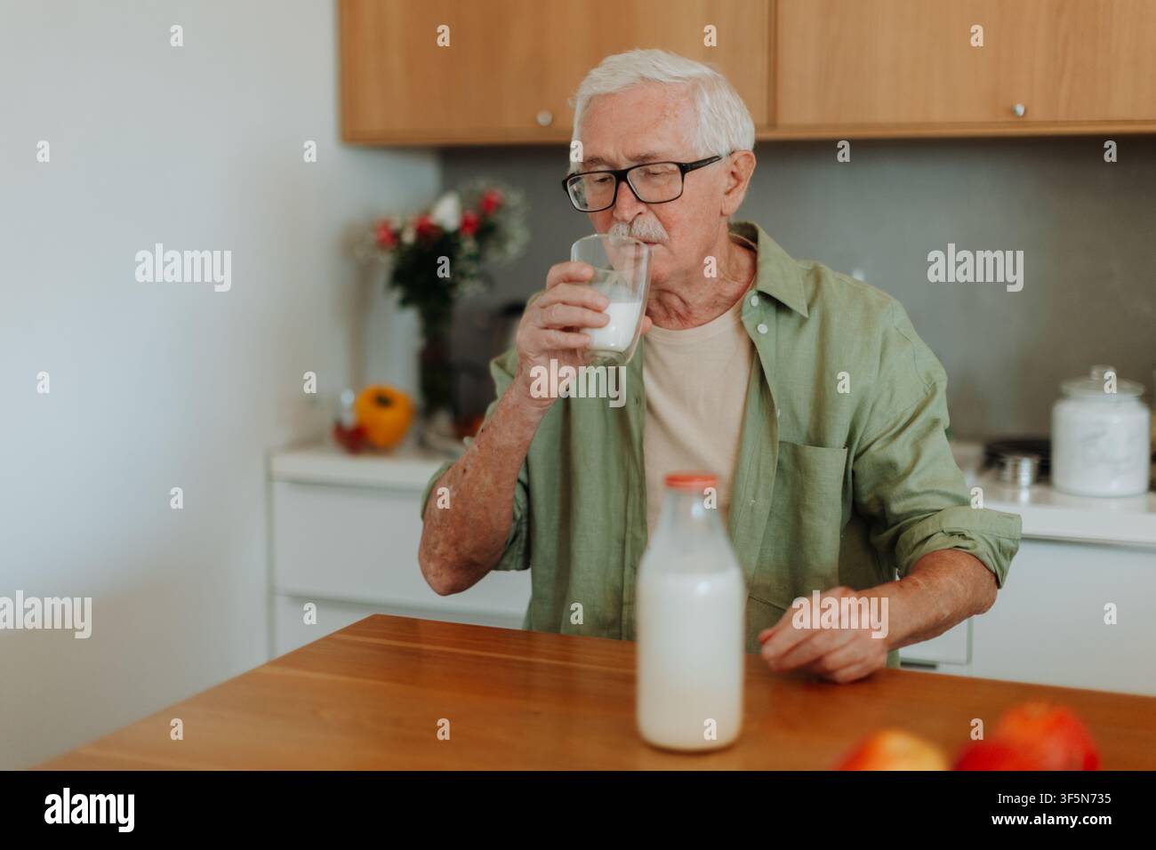 Smiling senior man drinking milk in kitchen. Stock Photo