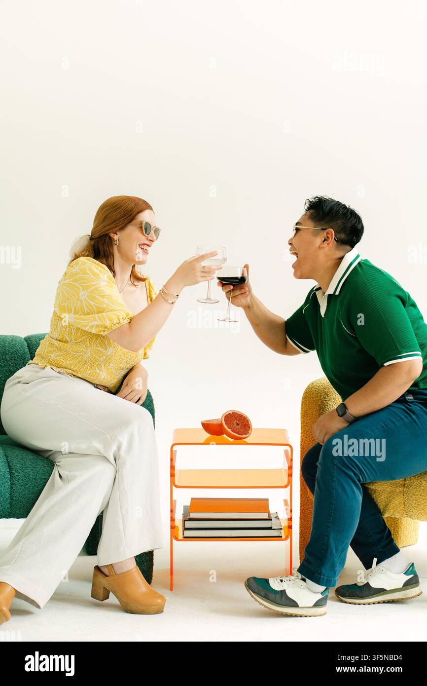 Two stylish people laugh while toasting wine Stock Photo