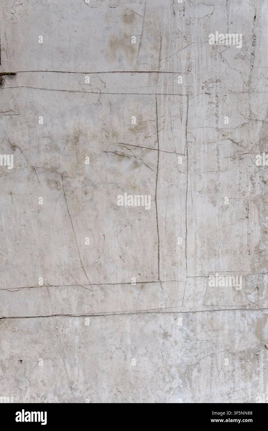 Concrete wall background with deep cracks and incised geometric lines. Aged cement surface with rough gray textures and industrial grunge patterns. Stock Photo